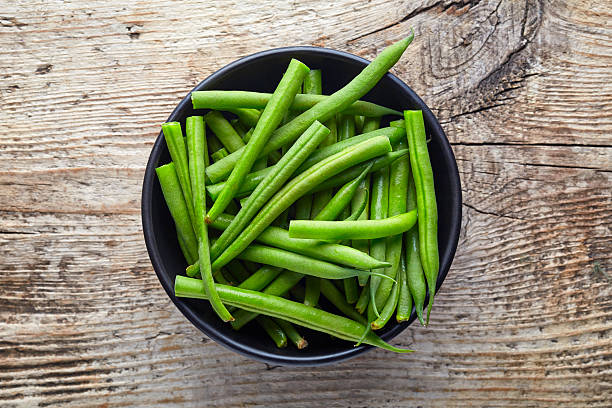istock Bowl of green beans on wooden table, from above 628364508