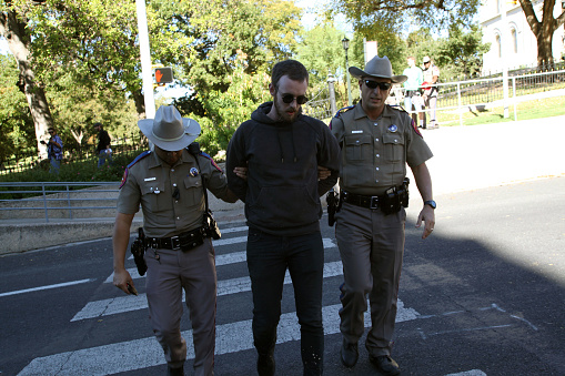 Austin, Texas, USA - November 19, 2016: Texas Department of Public Safety troopers arrest a counter-demonstrator for assault during a 'White Lives Matter' demonstration just south of the Capitol. The 'White Lives Matter' demonstrators, numbering about 20 people at the most, came from Houston with the message that the federal hate crime law is unfair to white people.