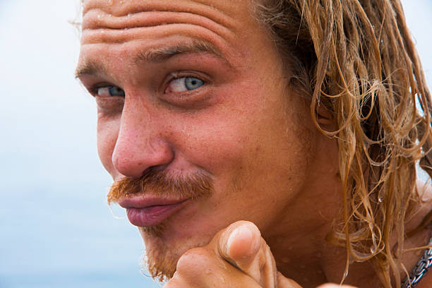 portrait of a wet blue eyed blond young man pointing at you