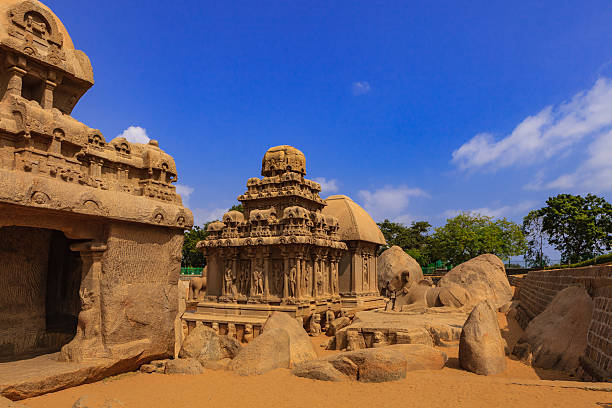 Mahabalipuram, India: 1300 Year Old Pancha Rathas, sculpted in Granite Image shows the Arjuna and Draupadi Rathas of the Pancha Rathas (also known as Pandava Rathas), a monument complex at Mahabalipuram or Mamallapuram, on the Coromandel Coast of the Bay of Bengal, in the state of Tamil Nadu, India. Dating from the late 7th century, it is attributed to the reigns of King Mahendravarman I and his son Narasimhavarman I (630–680 AD) of the Pallava Kingdom. The Arjuna Ratha is the monument in the centre, Nandi, the bull, can be seen to the right. To the left is a section of the Bhima Ratha and behind the Arjuna Ratha, is the Draupadi Ratha.The structures are without any precedence in Indian temple architecture and are carved out of a single granite rock each. Remarkably well preserved for monuments that are over 1300 years old; they withstood the ravages of the Tsunamis of the 13th Century and 2004. They however display the effects of wind and sand erosion of over a thousand three hundred years. These are not temples as they are unfinished, and were never consecrated. They are part of the UNESCO World Heritage site at Mahabalipuram. Photo shot in the afternoon sunlight; horizontal format. dravidian culture stock pictures, royalty-free photos & images