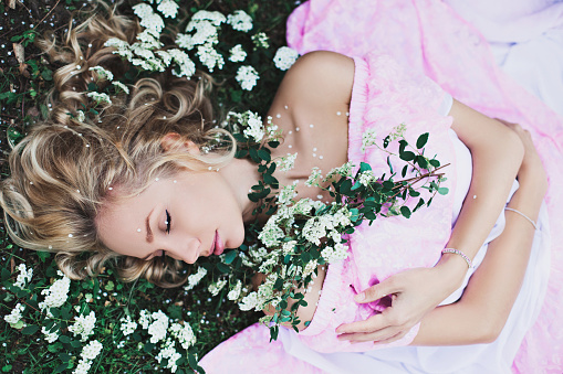 Beautiful woman relaxing on a green meadow with white flower
