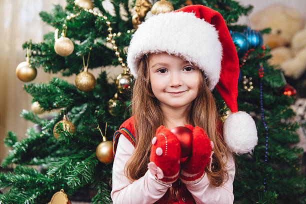 istock Cute girl in red hat hold a tree decoration 628410976