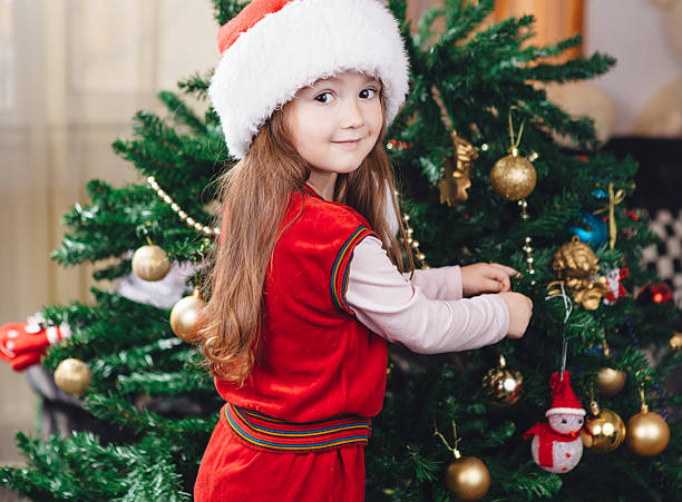 istock Little girl in red hat decorates a christmas tree 628411576