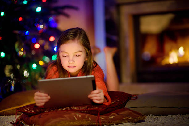istock Adorable little girl using tablet pc by fireplace on Christmas 628418732