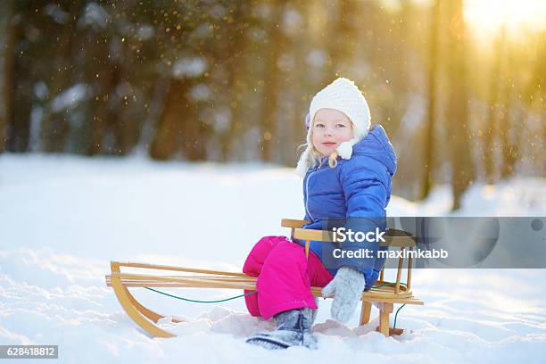 Funny Little Girl Having Fun With Sleigh In Winter Park Stock Photo - Download Image Now