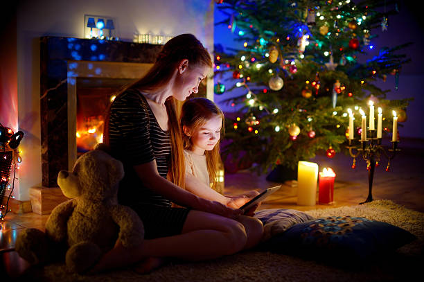 istock Mother and daughter using tablet by fireplace on Christmas 628418912