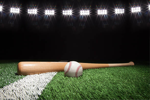 baseball and bat at night under stadium lights - baseball bat fotos imagens e fotografias de stock