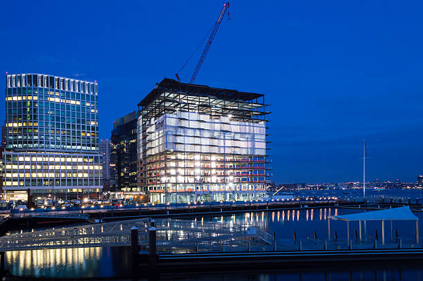 New construction Boston waterfront pre-dawn South Boston, Massachusetts, USA - December 8, 2016:  Rising steel frame of 50 Liberty project in South Boston overlooks Boston harbor just before dawn harborwalk stock pictures, royalty-free photos & images