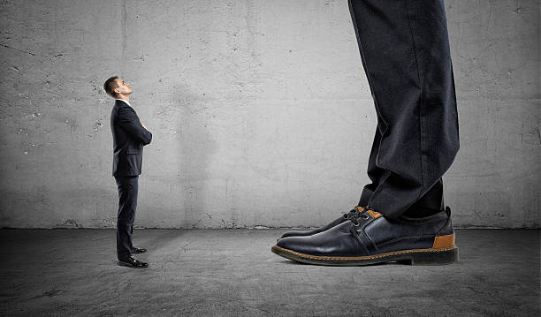 Tiny businessman looking up on huge legs of another man Tiny businessman looking up on huge legs of another businessman. Career growth and opportunities. Confident behaviour. subordination stock pictures, royalty-free photos & images