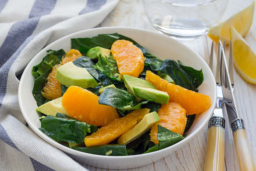 Healthy spinach, avocado and orange salad with ginger-vinegar dressing, horizontal