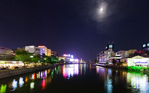 Glowing shot of the riverfront area of Fukuoka, Japan, with the moon shining down. Still taken from time lapse video #542878262.