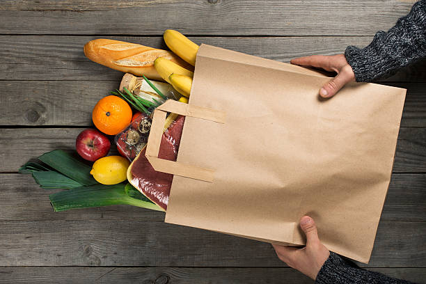 木製のキッチンで異なる健康的な食べ物の袋を保持している男 - paper bag groceries food vegetable ストックフォトと画像