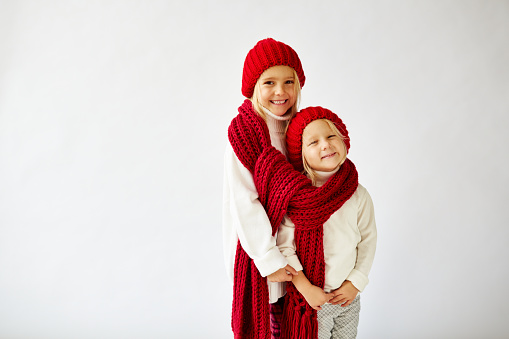 Lovely little sisters wearing warm knit hats and scarf