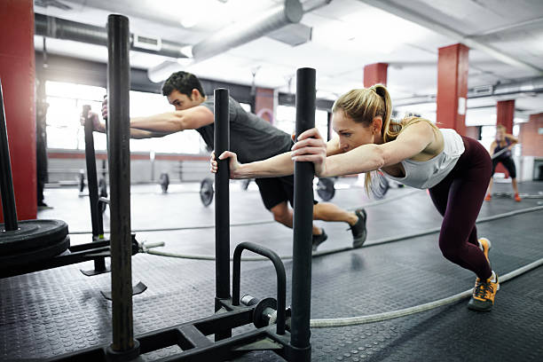 I believe in the person I want to become Shot of two people pushing weight sleds in a gym prowling stock pictures, royalty-free photos & images