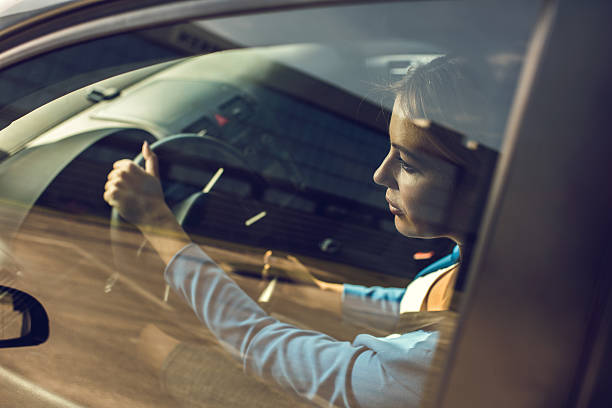 Young serious businesswoman driving a car.