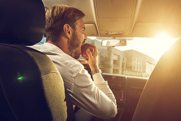 Young businessman eating an apple in the car.