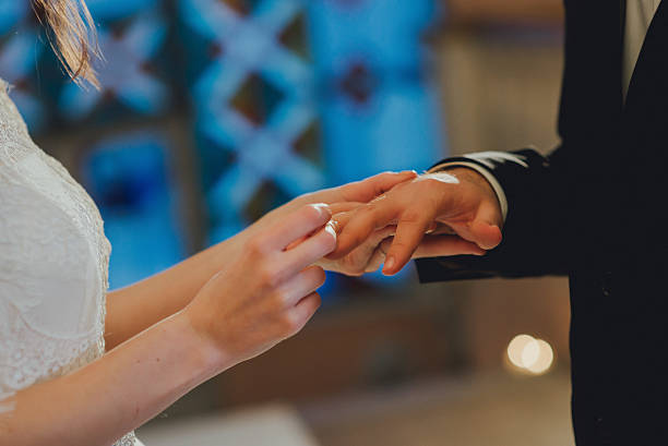 istock groom's hand putting a wedding ring on the bride 628461588