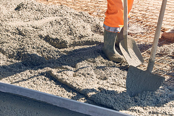 Concrete pouring during commercial concreting floors of building Worker with gum boots spreading ready mix concrete contracting stock pictures, royalty-free photos & images