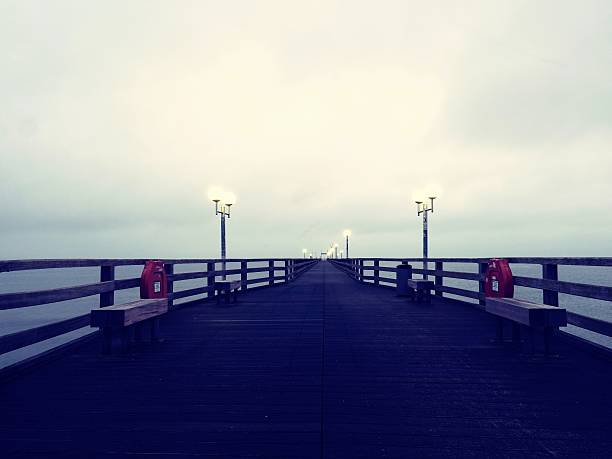 istock Pier at misty night with yellow lights,  dark blue sky 628463924