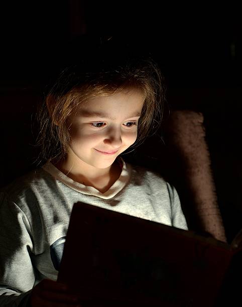 istock Young girl reading book at night 628464148