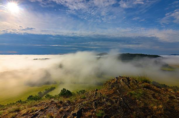 istock Basalt peak on hill. Forest valley  and Sun above mist. 628464190