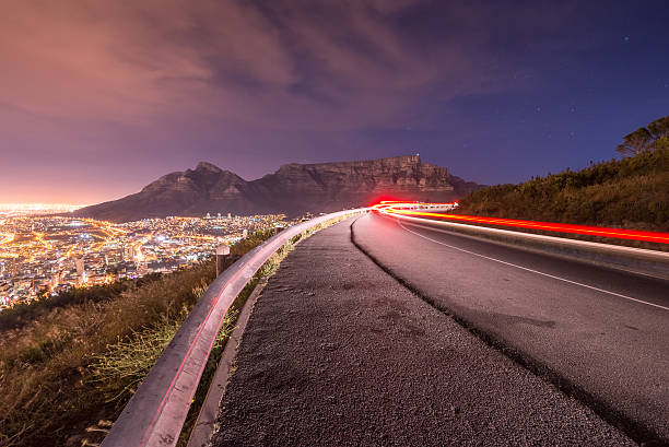 Cape Town Long exposure of a car driving around a bend with Table Mountain in the background in Cape Town as seen from Signal hill. cape peninsula photos stock pictures, royalty-free photos & images