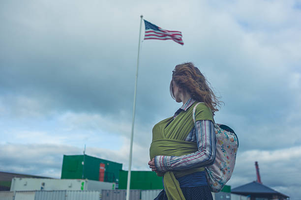 American flag showing it's colors in front of a Cloudy Sky and hills and forest