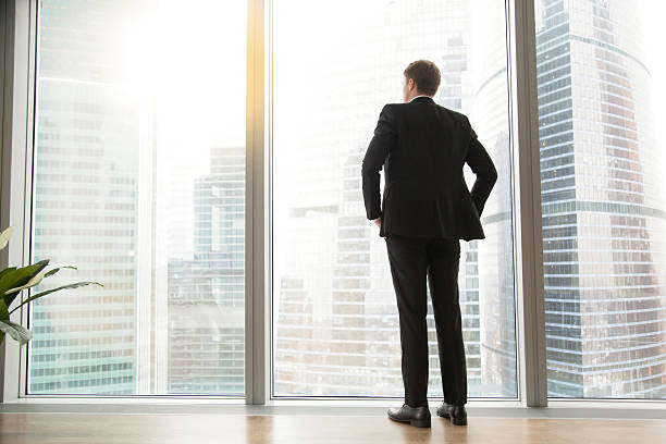 vue arrière longue et pleine longueur d’un homme d’affaires prospère dans une grande ville - rear view businessman thinking men photos et images de collection