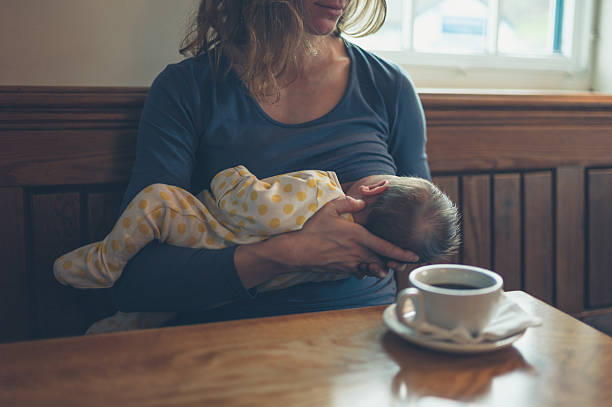 Woman breastfeeding baby in cafe stock photo