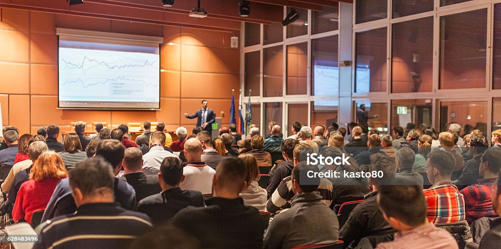 Business speaker giving a talk in conference hall. Speaker giving a talk in conference hall at business event. Audience at the conference hall. Business and Entrepreneurship concept. Meeting Stock Photo