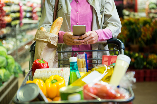 Mujer que usa el teléfono móvil mientras compra photo