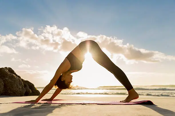 Photo of Athlete in downward facing dog position on shore