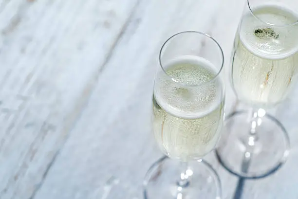 Two glasses of Prosecco or Champagne on a garden picnic table outdoors in Springtime or Summertime.