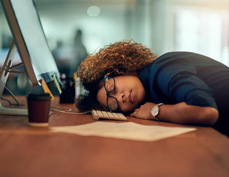Shot of an exhausted young businesswoman sleeping at her desk during a late night at work