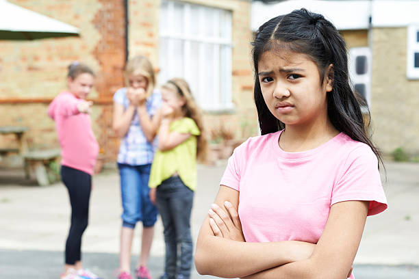 Unhappy Girl Being Gossiped About By School Friends Unhappy Girl Being Gossiped About By School Friends sad child standing stock pictures, royalty-free photos & images
