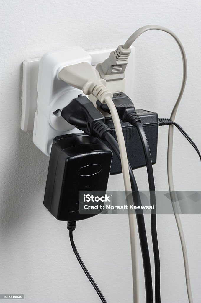 Overloaded Multiple electrical plugs in wall outlet Electrical Outlet Stock Photo