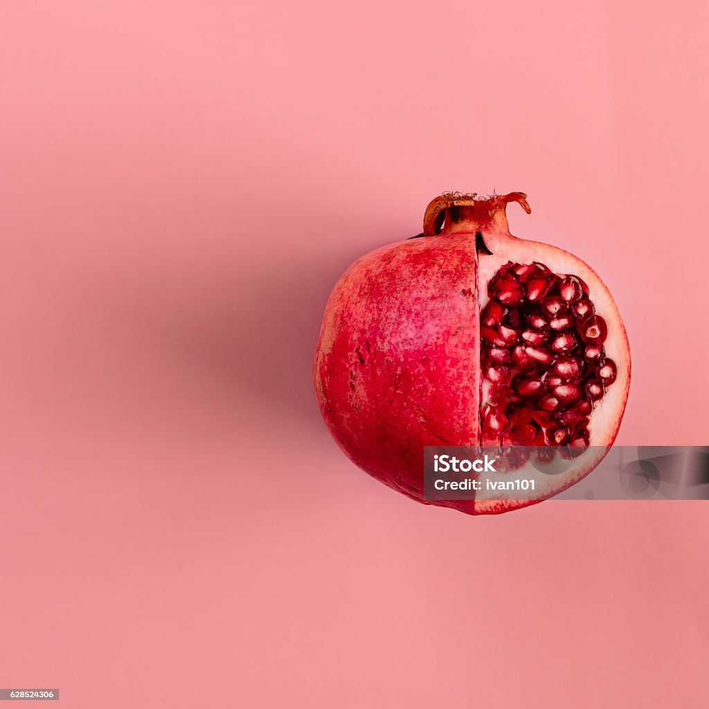 Red pomegranate fruit on pastel pink background. Minimal flat la Red pomegranate fruit on pastel pink background. Minimal flat lay concept. Pomegranate Stock Photo