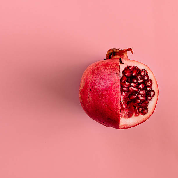 Red pomegranate fruit on pastel pink background. Minimal flat la Red pomegranate fruit on pastel pink background. Minimal flat lay concept. pomegranate stock pictures, royalty-free photos & images