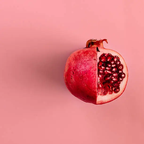 Photo of Red pomegranate fruit on pastel pink background. Minimal flat la