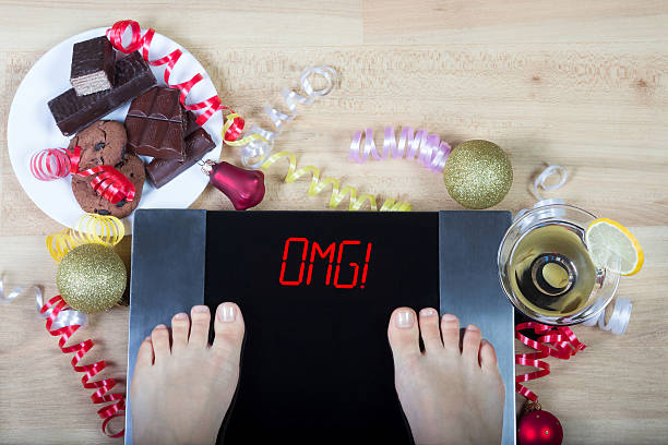écailles avec le signe « omg! » entouré d’aliments malsains et d’alchohol. - holiday healthy lifestyle weight christmas photos et images de collection