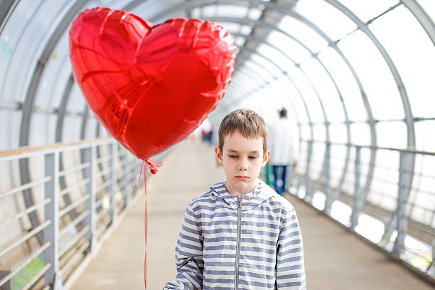 istock sad boy with red heart in hands 628527024