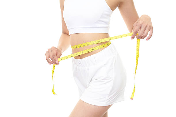 Successful woman on diet Body of woman with a measuring tape. exercising tape measure women healthy lifestyle stock pictures, royalty-free photos & images