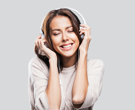 Happy young woman wearing headphones listening to the music