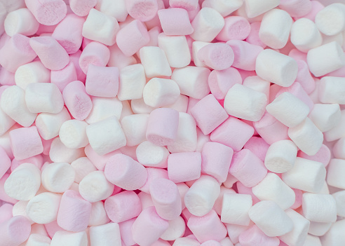 Pink and white mini marshmallows background, close-up texture. A pile of different mini puffy marshmallows. Marshmallow concept. Wallpaper for desktop. Top view.