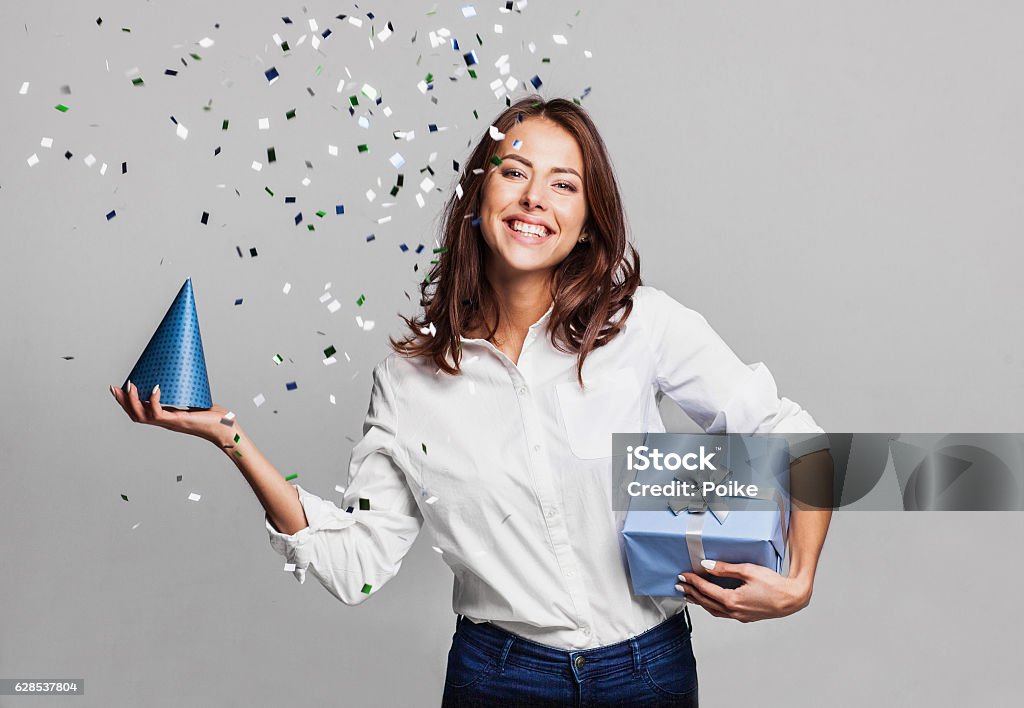 Laughing girl with falling confetti at party Beautiful woman with confetti and gift box at party on gray background Gift Stock Photo