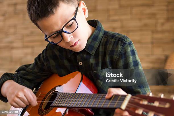Boy With Glasses Playing Acoustic Guitar In Living Room Stock Photo - Download Image Now