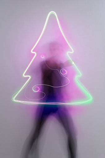 man in aktion drawing light trail symbols with laserpointer, time exposure, christmas tree icon