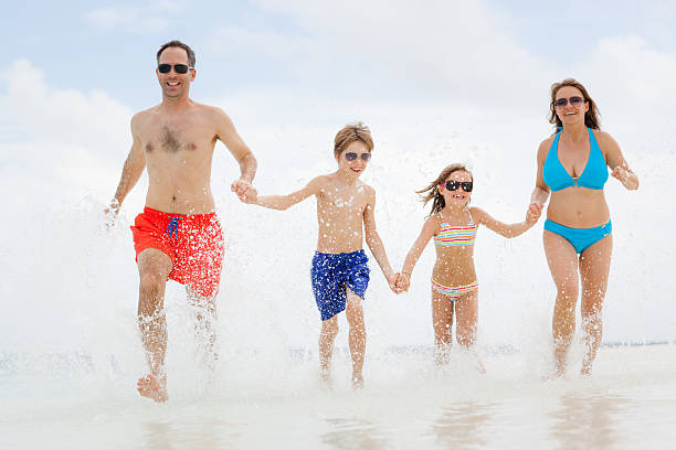 istock parents children running splashing water beach 628550624
