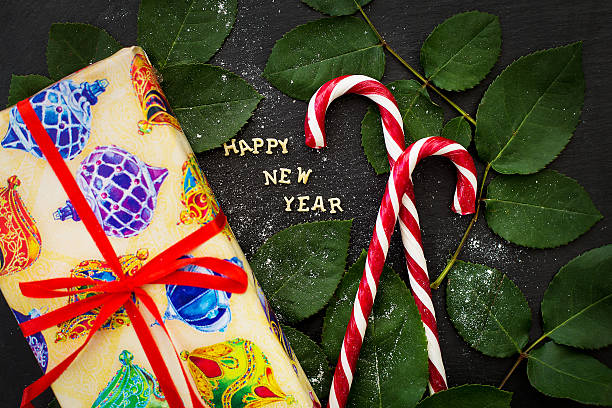 Postcard to winter holidays inscription of new year on a black board with gift and red candy. lieke klaus stock pictures, royalty-free photos & images