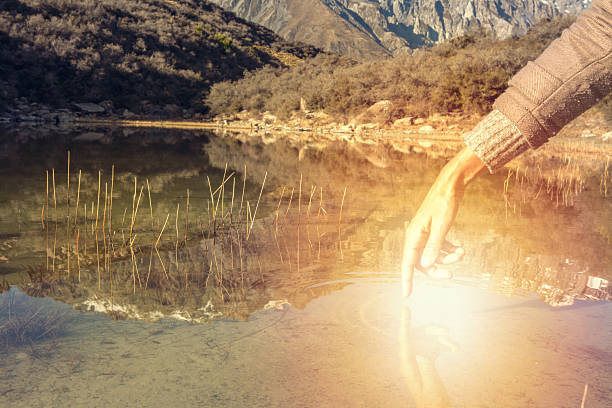 istock Finger touches surface of mountain lake 628552172